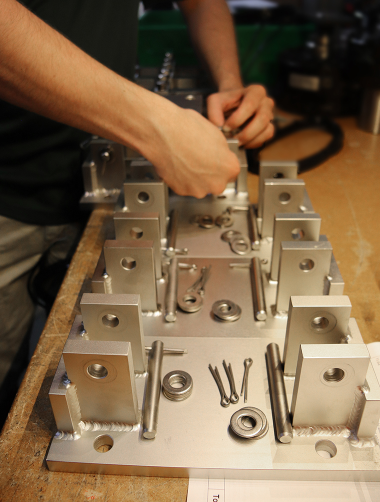 Technician building load cell mounting assemblies for a system